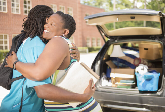 Mom hugging son unpacking car when dropping off for college