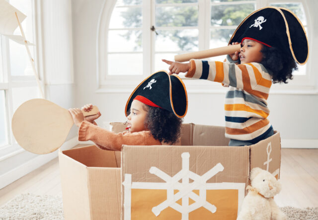 Two girls playing dress up with pirate costumes and a cardboard box
