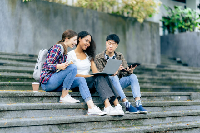 Three college students talking and working together in a park.